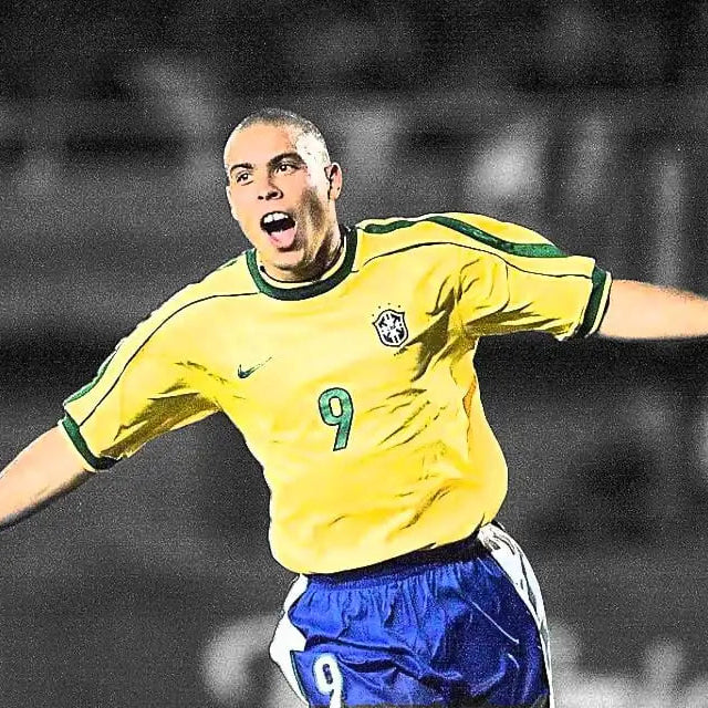 Soccer player in a yellow jersey with blue shorts celebrating on a blurred background