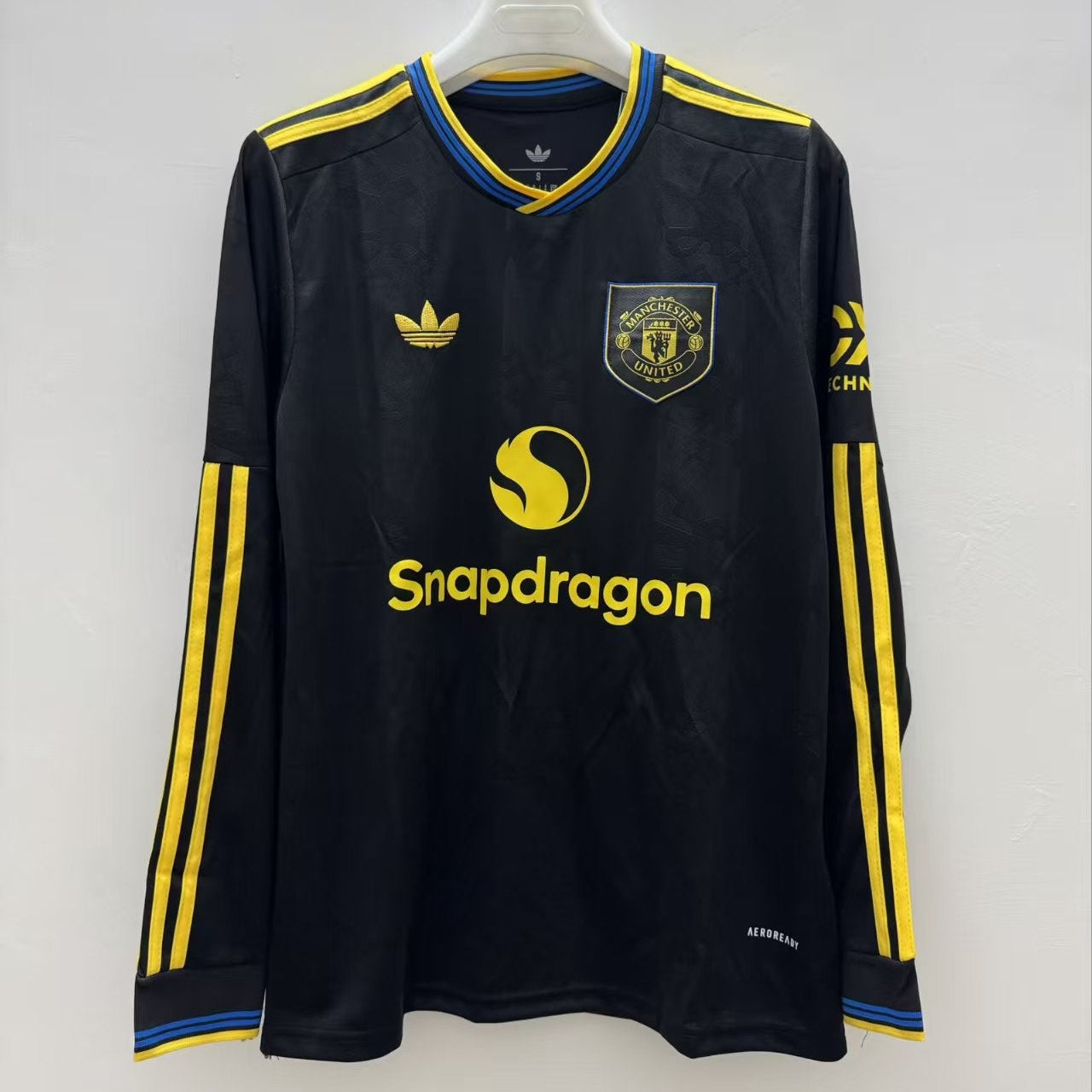 Black sports jersey with yellow accents and branding on a white background