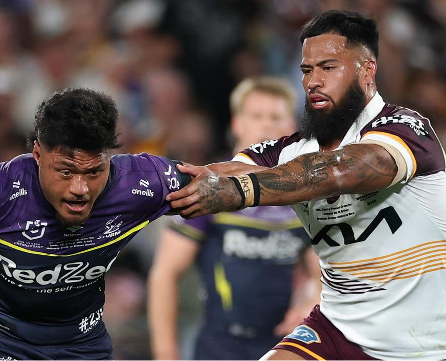 Two rugby players in action during a match, one in a purple jersey and the other in a white and brown jersey.