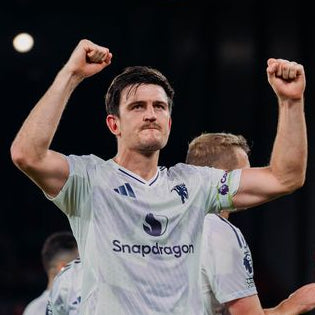 Soccer player celebrating with arms raised on a dark background