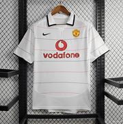 Front view of the Manchester United Third Jersey 2003/04 in white with fine horizontal pinstripes, fold-over collar, club crest, chest logo, and Vodafone sponsor