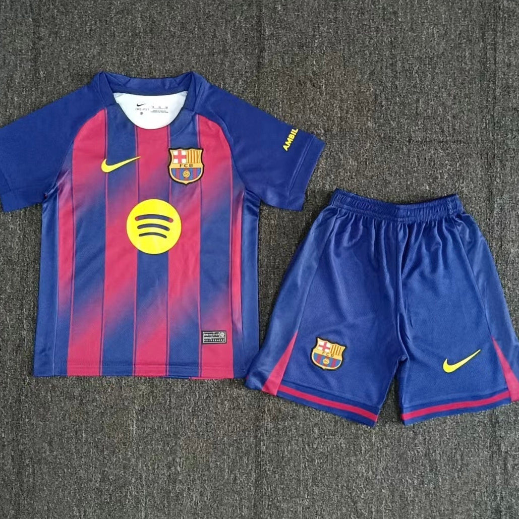 Nike Barcelona home kit 2025 26 kids front view red and blue striped jersey with shorts
