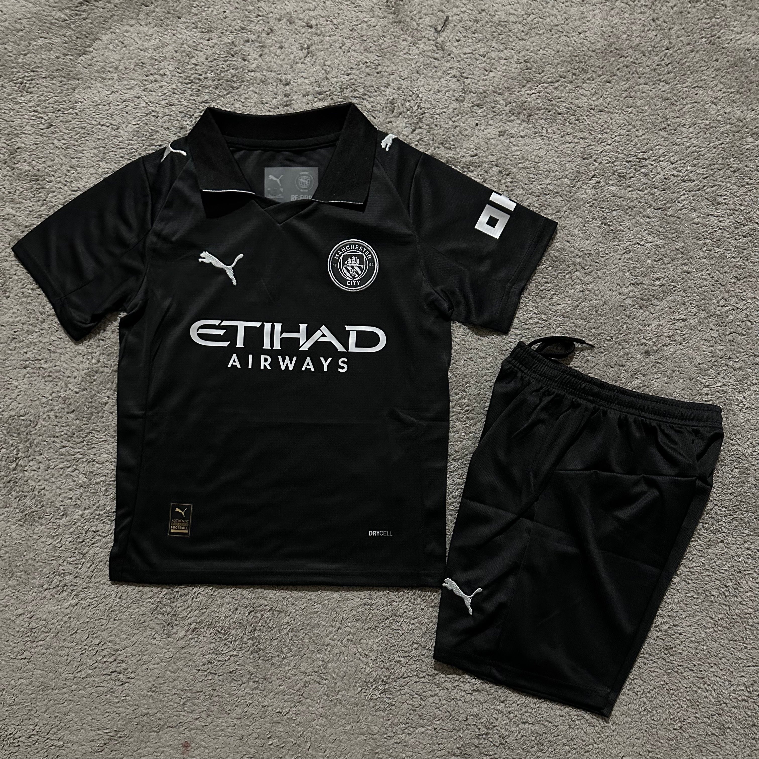 Puma Manchester City away kit 2025 26 kids front view black jersey and shorts
